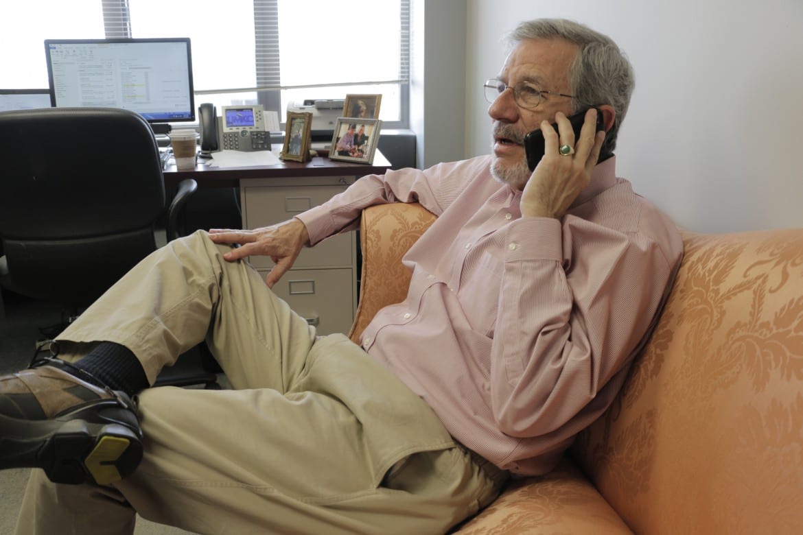 Man sitting on the couch in an office, talking on the phone.