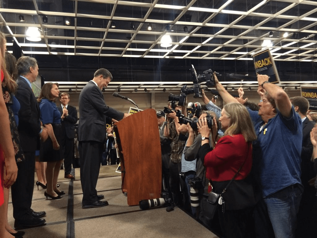 Photo of Sam Brownback at podium addressing crowd
