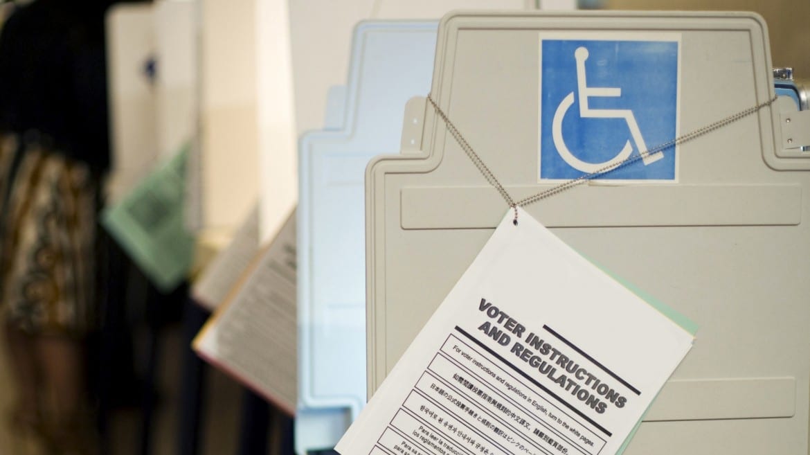 Photo of voting booth with handicap symbol and "Voter Instructions and Regulations" book