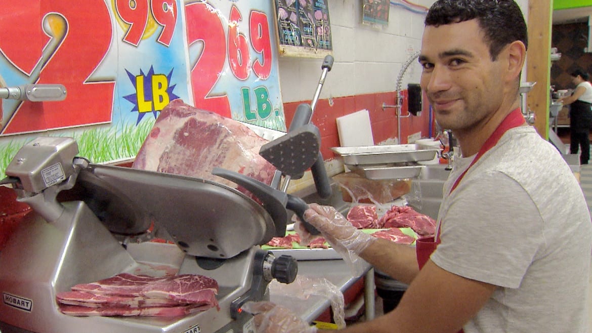A grocery worker slices meat behind the counter at La Vazquez Market in Lexington, Neb. (Photo: Brian Seifferlein | Harvest Public Media)