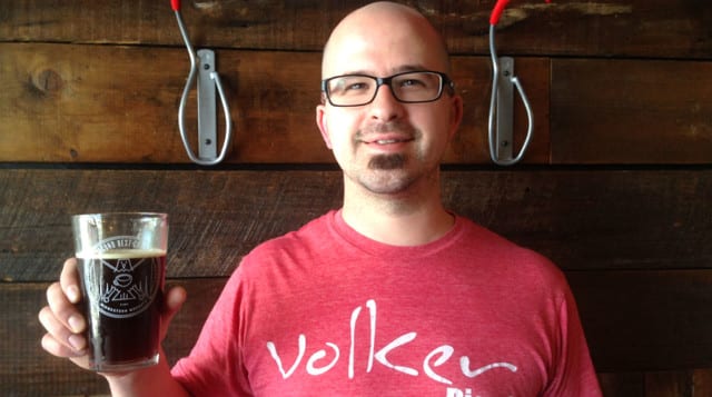 Nathan Anderson, co-owner of Second Best Coffee, holds up a pint of the Nitro cold brew coffee. (Credit: Pete Dulin)