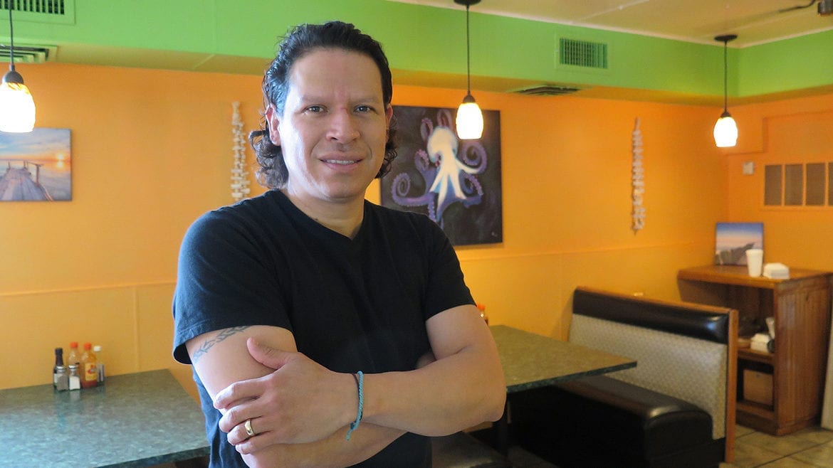 A man standing in his restaurant.