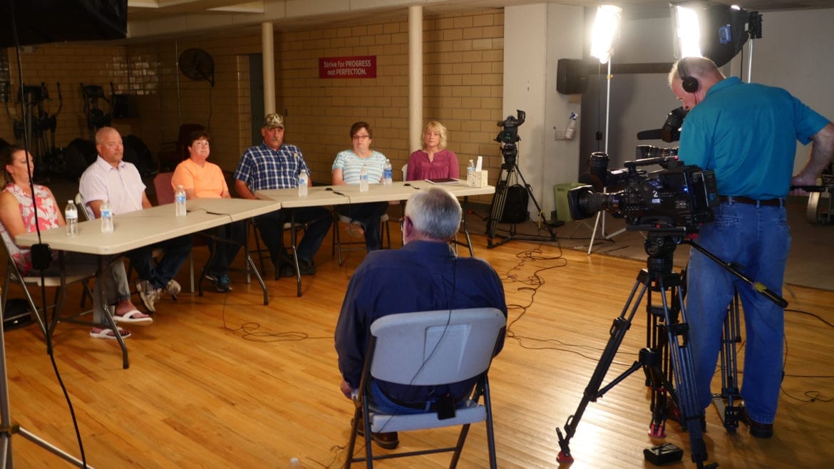 A reporter and videographers talking to seated family members