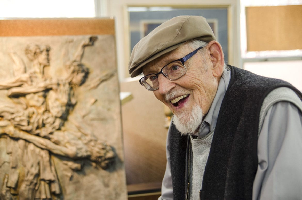 A man speaking near his painting.