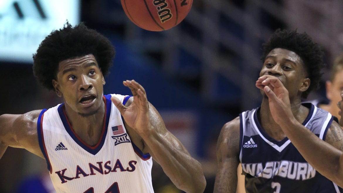 Two basketball players running for the ball.
