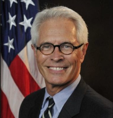 A man's headshot with an American flag behind him