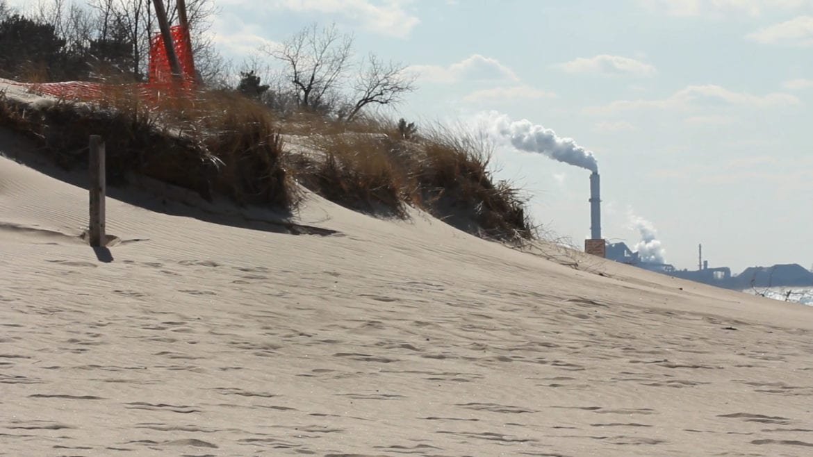 A beach with a visible smokestack in the background