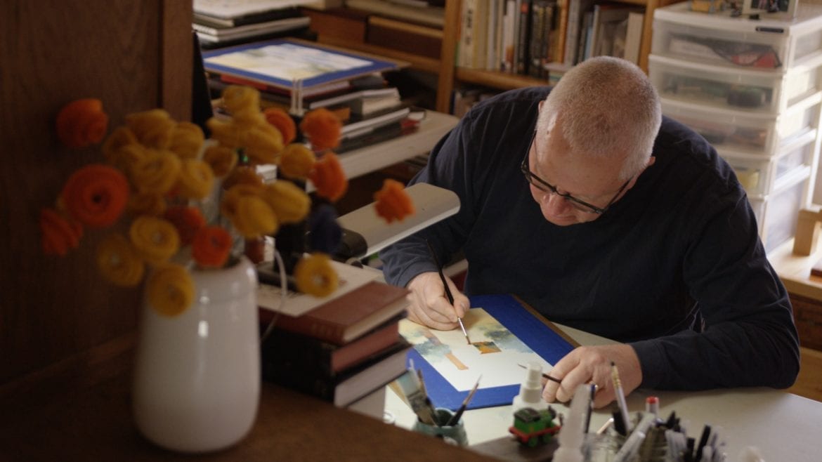 A man painting with watercolors at his desk