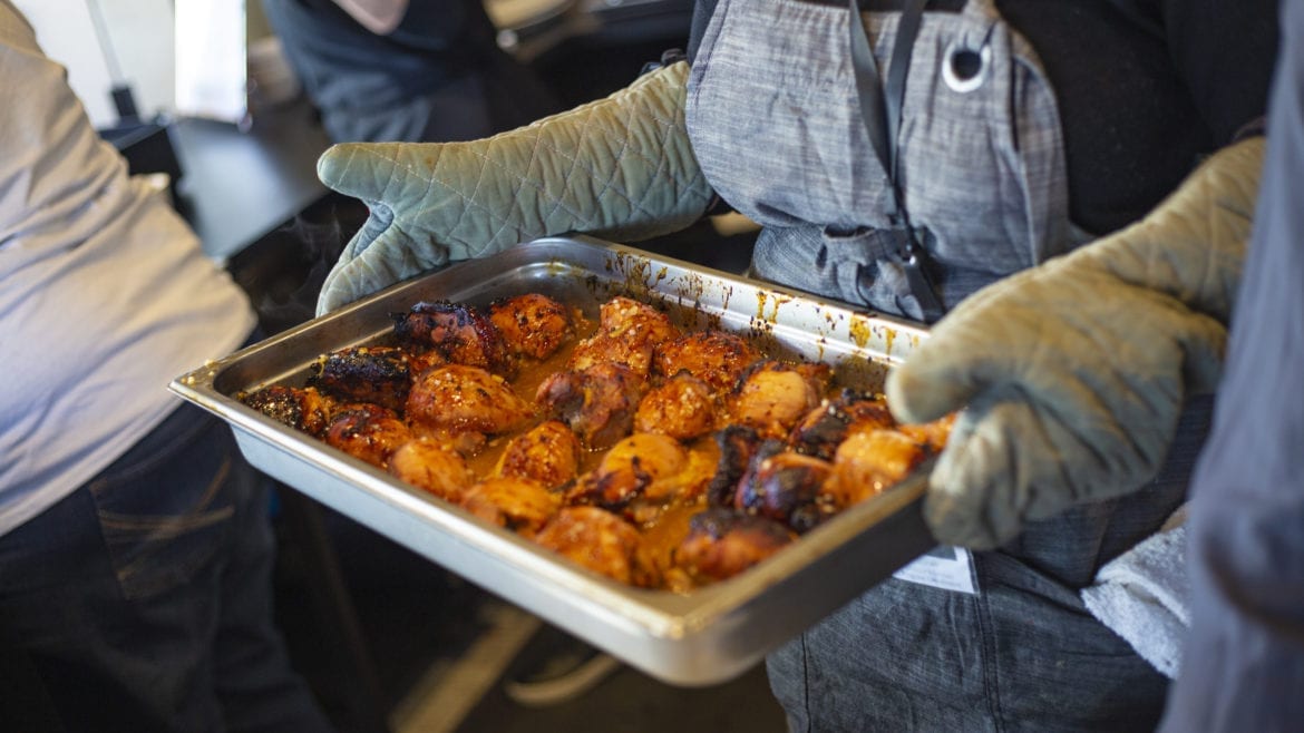 Program coordinator Sarah Tepikian brings out a chili-rubbed chicken special