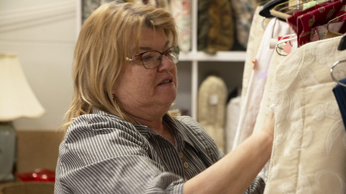 Sheryl Raineri arranges clothing at the Manor Thrift Shop in Liberty, Missouri.