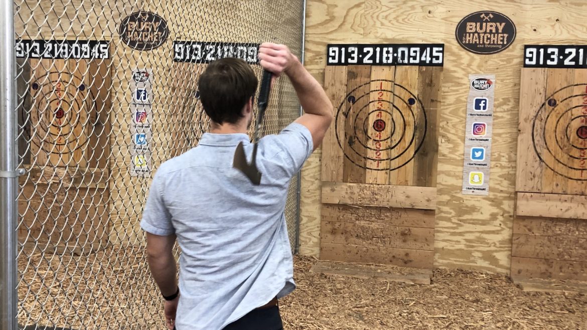 An axe thrower steps up and aims at a target.