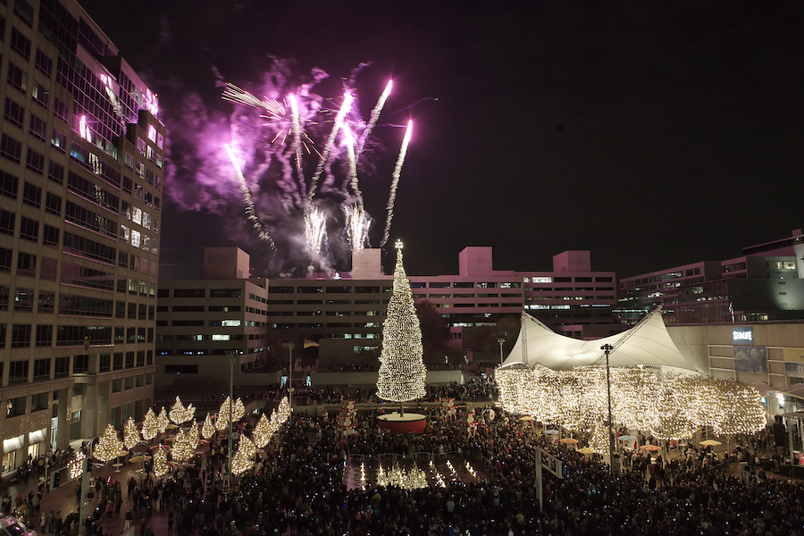 The Mayor's Christmas tree is lit with fireworks in the background. 