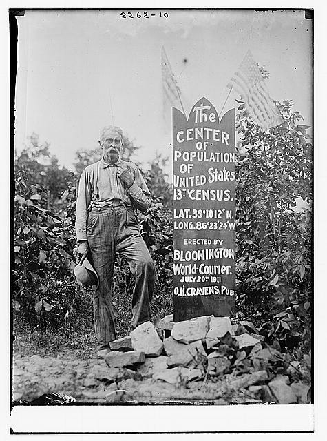 Man standing next to a sign that says "The Center of Population of the United States"