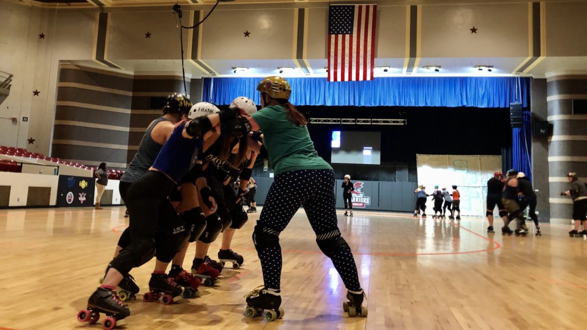 A bunch of skaters embrace one another at practice.