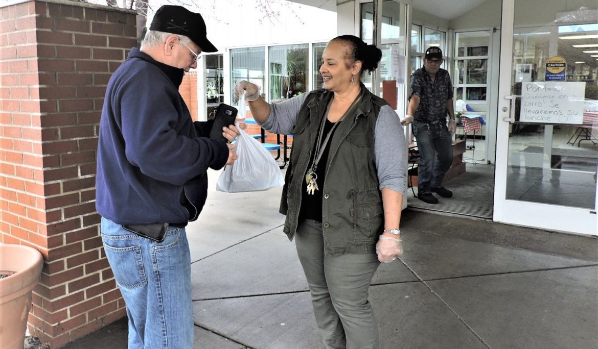 Staff member at Don Bosco Senior Center hands out a hot lunch.