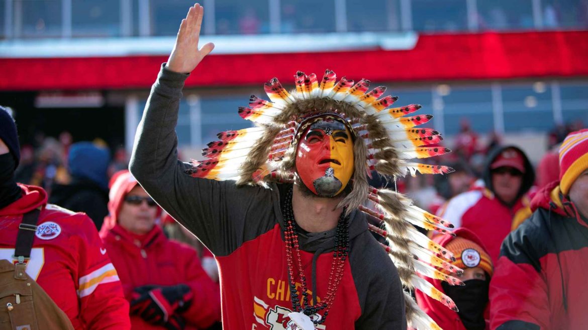 Chiefs fan in headdress doing the tomahawk chop