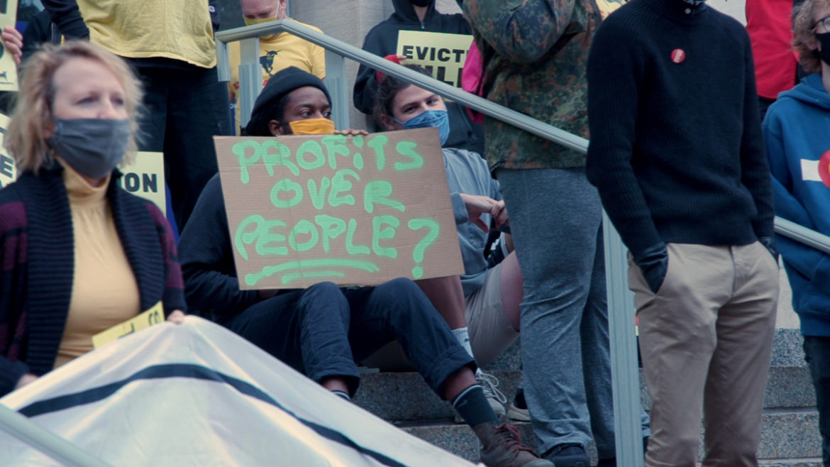 A protester holds a sign that says "People Over Profits" during a demonstration against eviction.