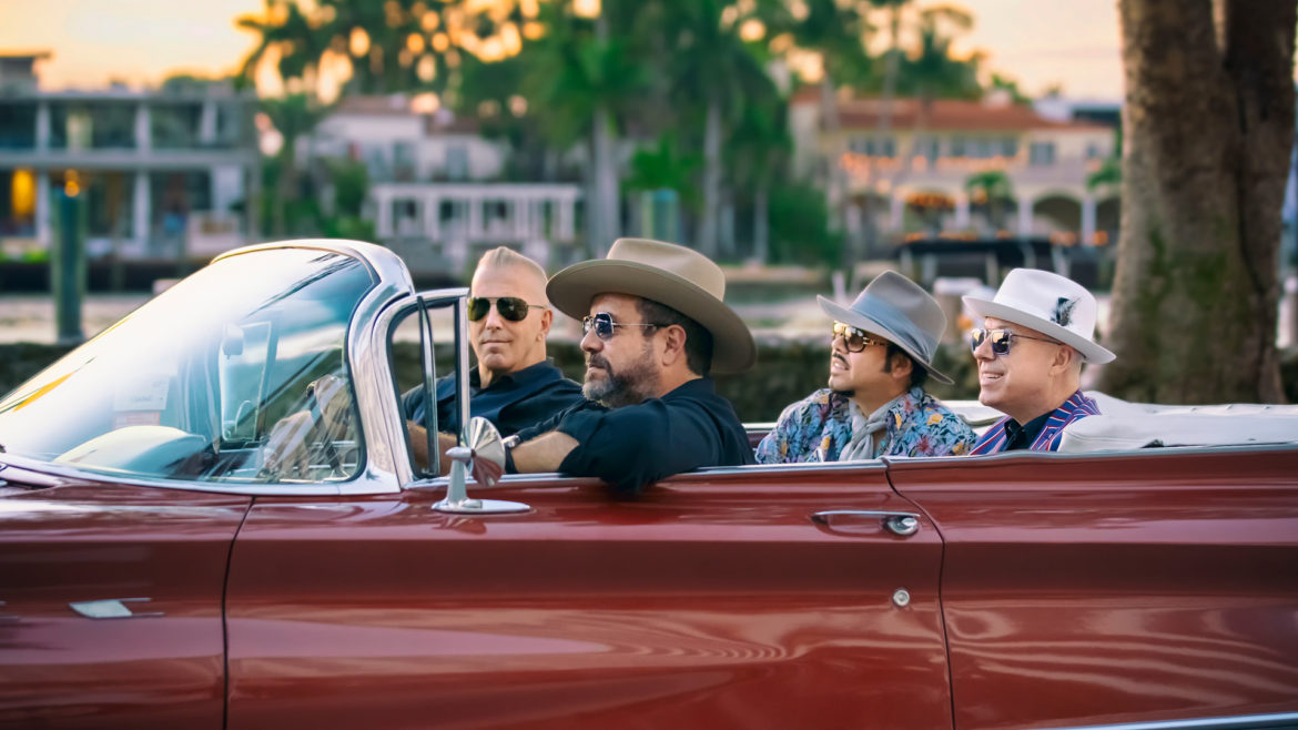 The Mavericks band rides in a convertible.