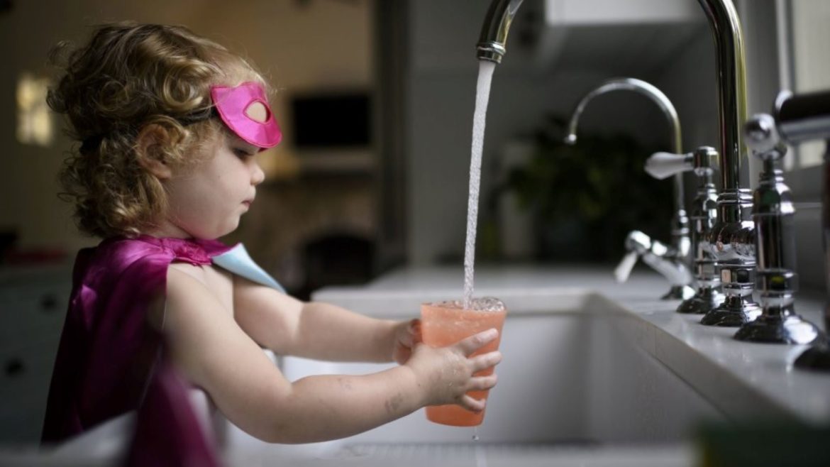 Girl getting water at a sink.