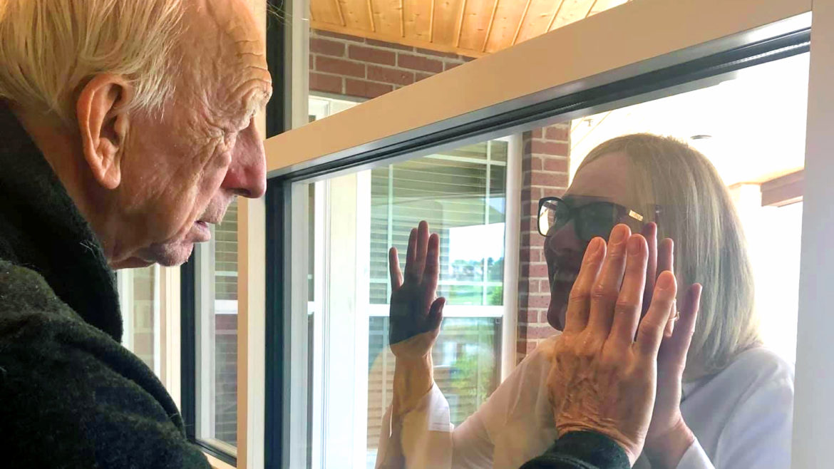 An unidentified family member visits through the window with their loved one at Cross Creek.