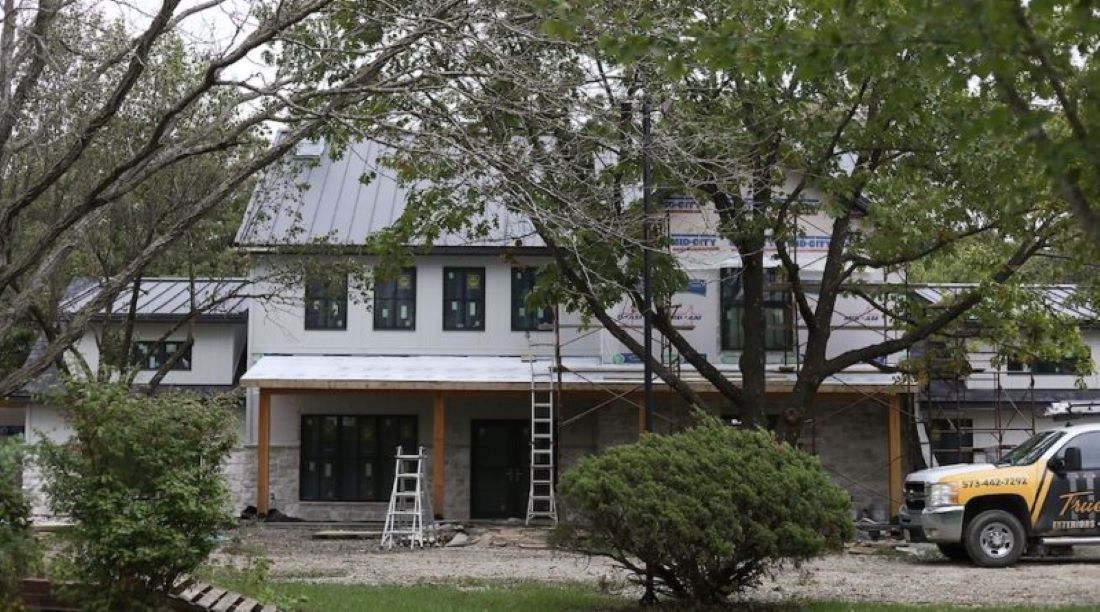 A TrueSon Exteriors truck and ladders sit outside a house renovation in Ashland.