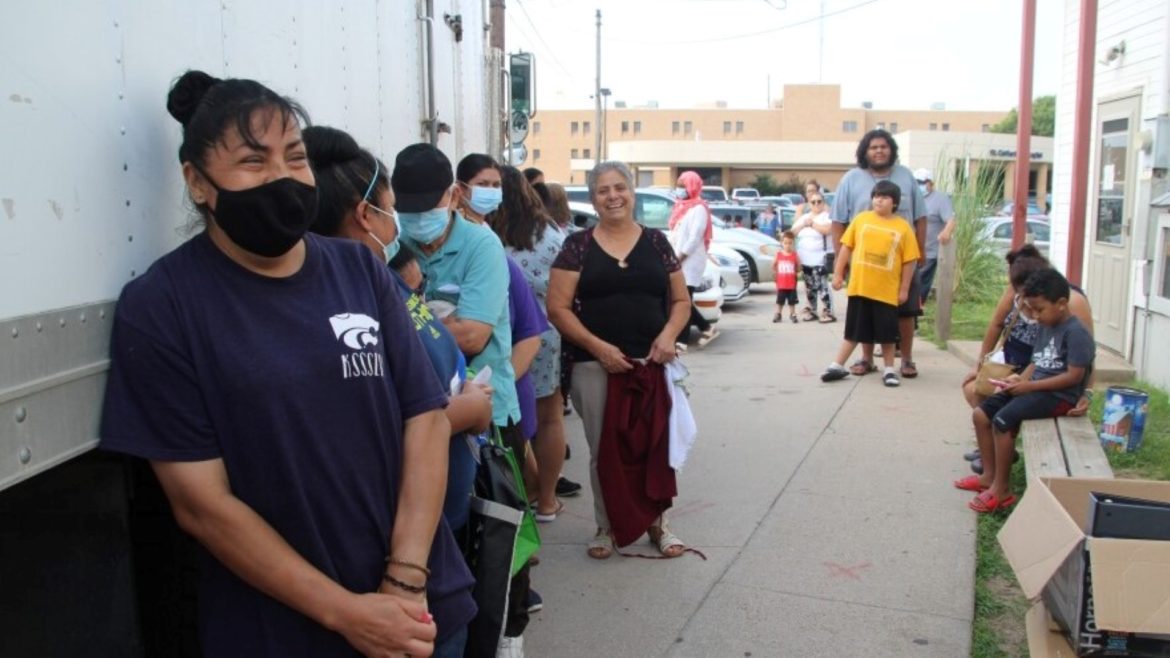 A line of people wait for the food pantry to open at Emmaus House. Maria Hernandez, center, cooks for the shelter's soup kitchen in addition to helping pass out groceries.