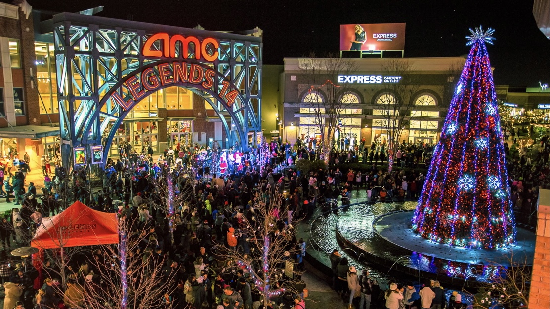 A crowd surrounding a lit Christmas tree at Legends.