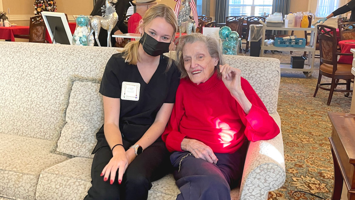 Felicia Honey, a nursing assistant, poses with a nursing home resident. Honey is a college student who's helped at Benton House of Lenexa during the historic staffing shortage.