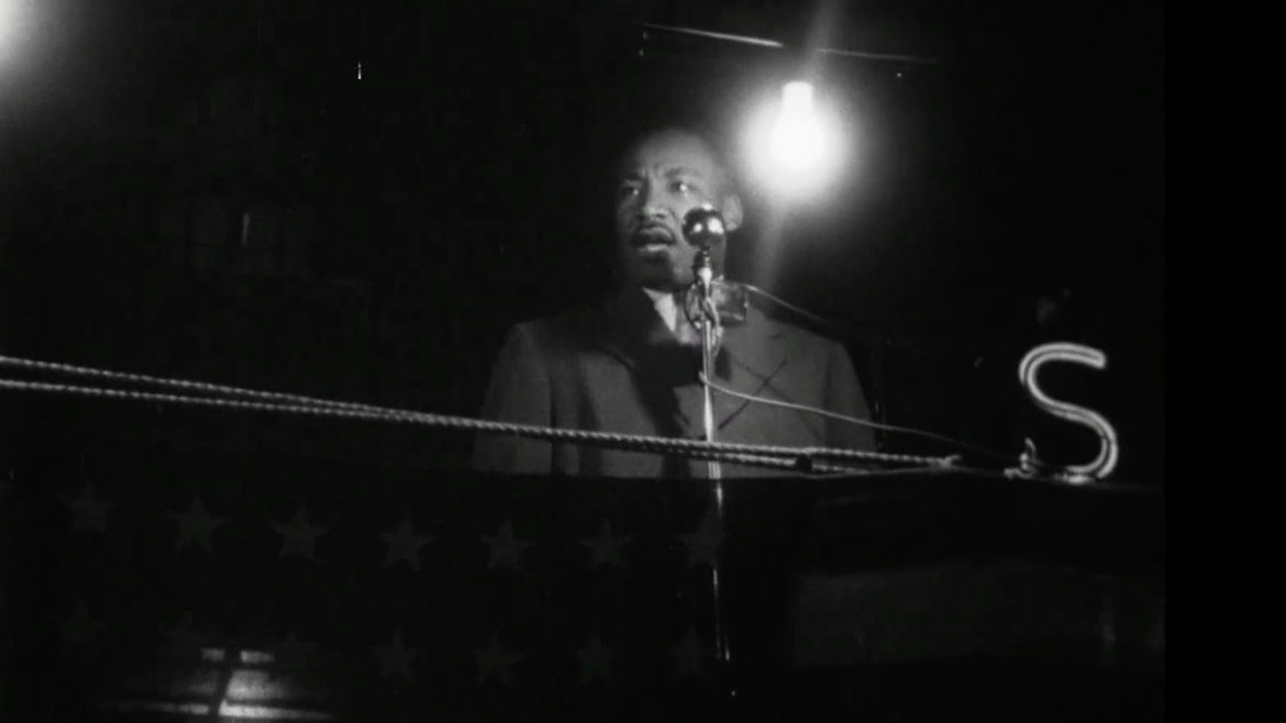 Martin Luther Jr. stands at a pulpit, with a light shining behind him. Jr. was a speaker at the Mammoth Rally on May 3 in the late 1950s.