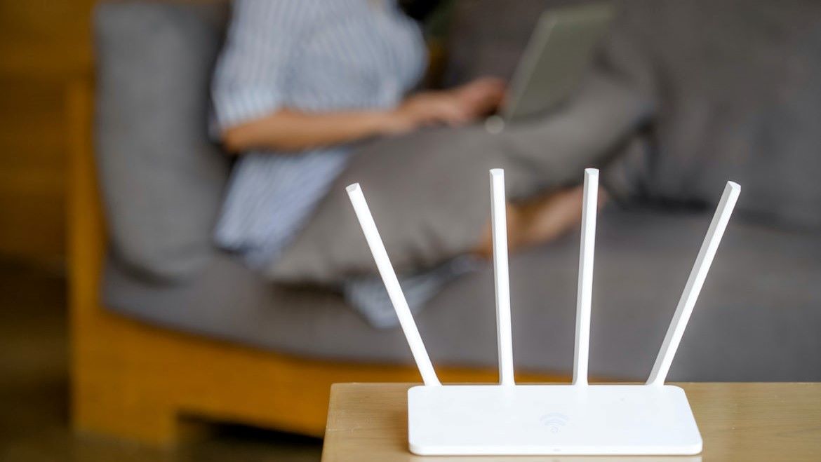 Wireless router and woman using a laptop in office.