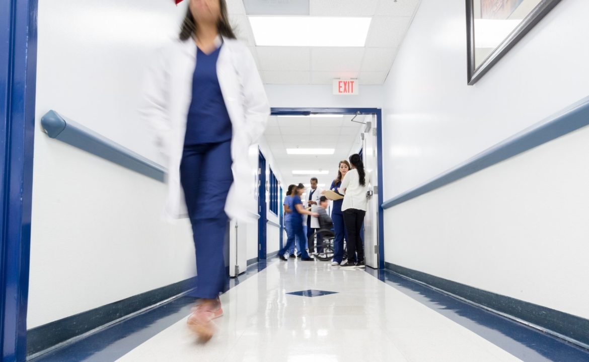 Medical staff walk through or aid patients in a hospital hallway. Image from Canva