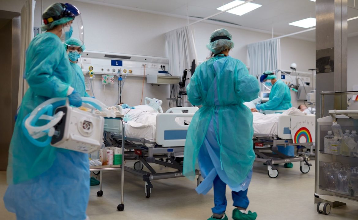 Hospital staff in Personal Protective Equipment such as robes, gloves and masks, treat a patient. This image accompanies our prompt that invites you, the public, to ask questions you want answered about health care.