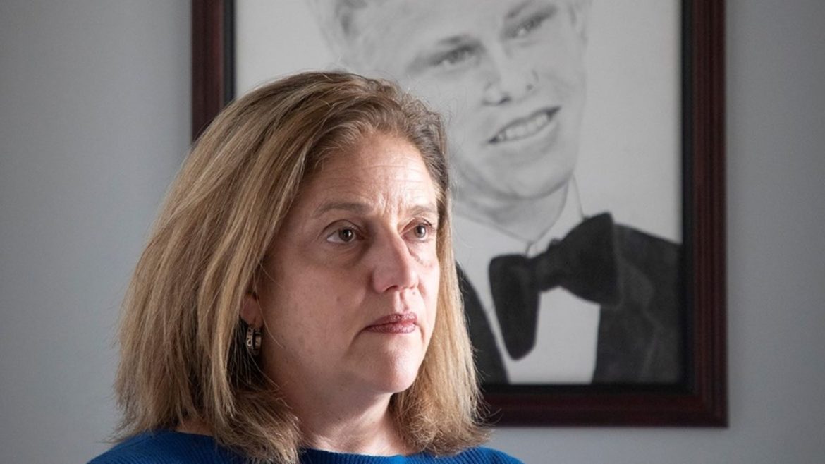 Sheila Albers in front of a portrait of her son, John, who was shot and killed by an Overland Park police officer.