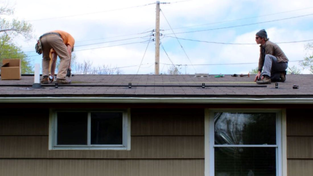 John Hooker and Mike Loesch begin installation of solar panels on the roof of a Columbia, Missouri, home.