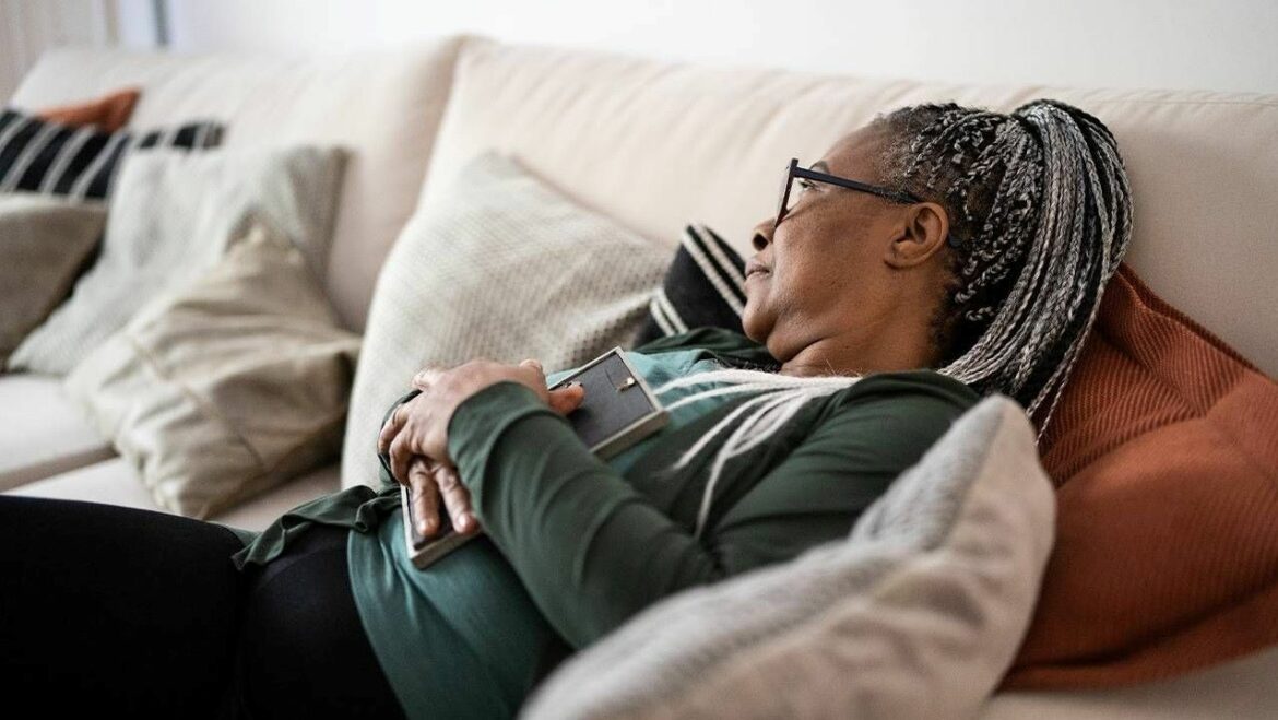 Photo illustration of a woman on a couch, gazing into the distance.
