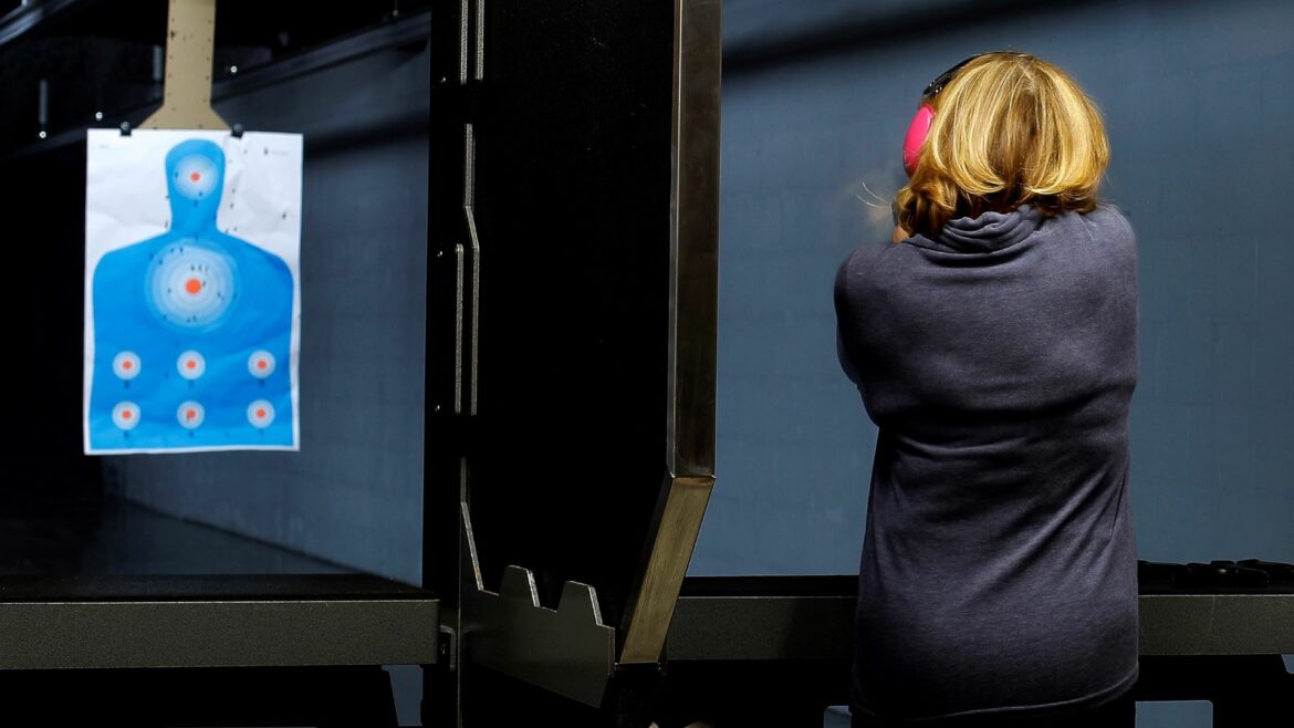 A woman takes aim at a target on the shooting range at Frontier Justice in Lee's Summit, Mo.