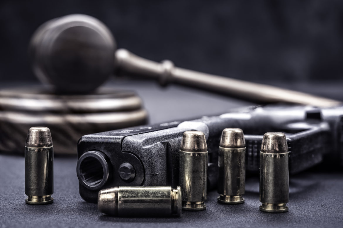Bullets lined up in front of a gun are propped in front of a gavel. This is illustrative of the Flatland Show's next topic: gun and safety. This month, the curiousKC and Flatland team discuss how to address gun violence in Kansas City. What questions about gun violence do you have?