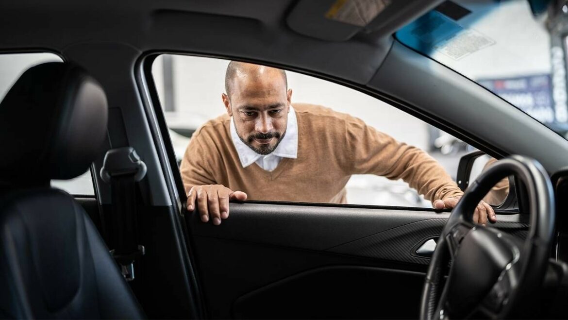 A man looks inside a new car.