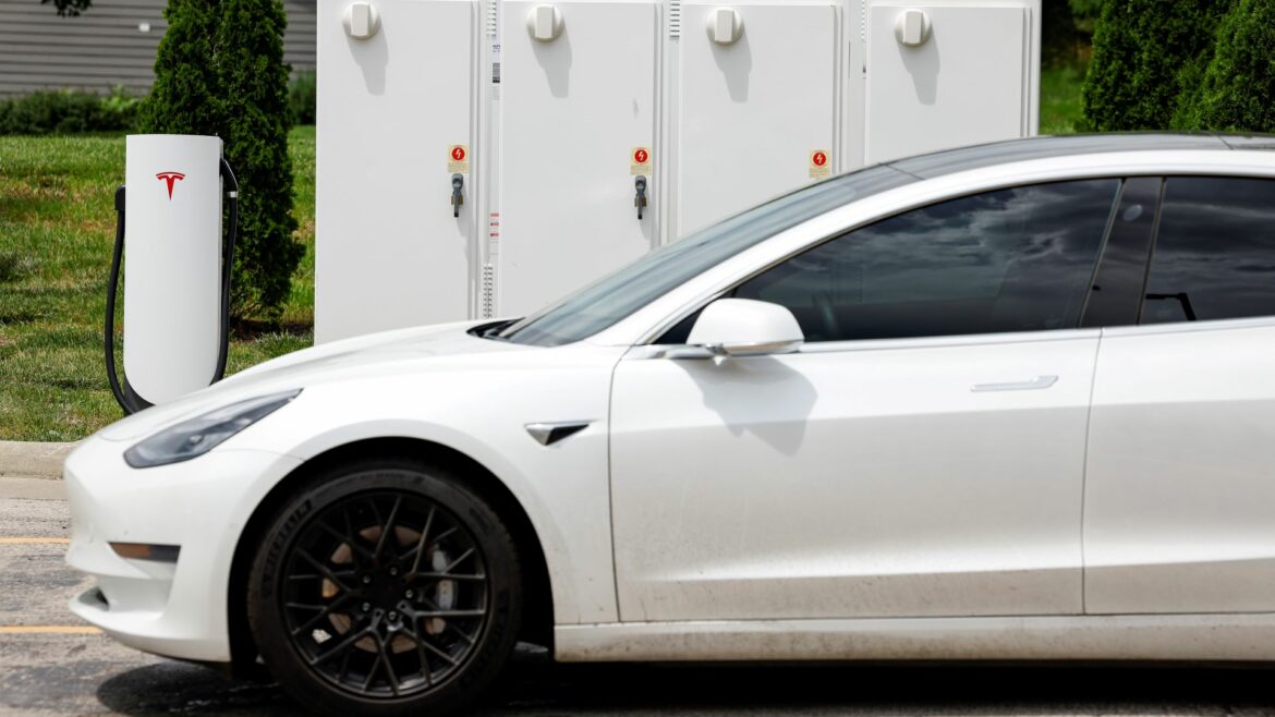 A detail view of a motorist charging their vehicle with a Tesla urban supercharger, Sunday, June 12, 2022, in Kansas City, Mo.