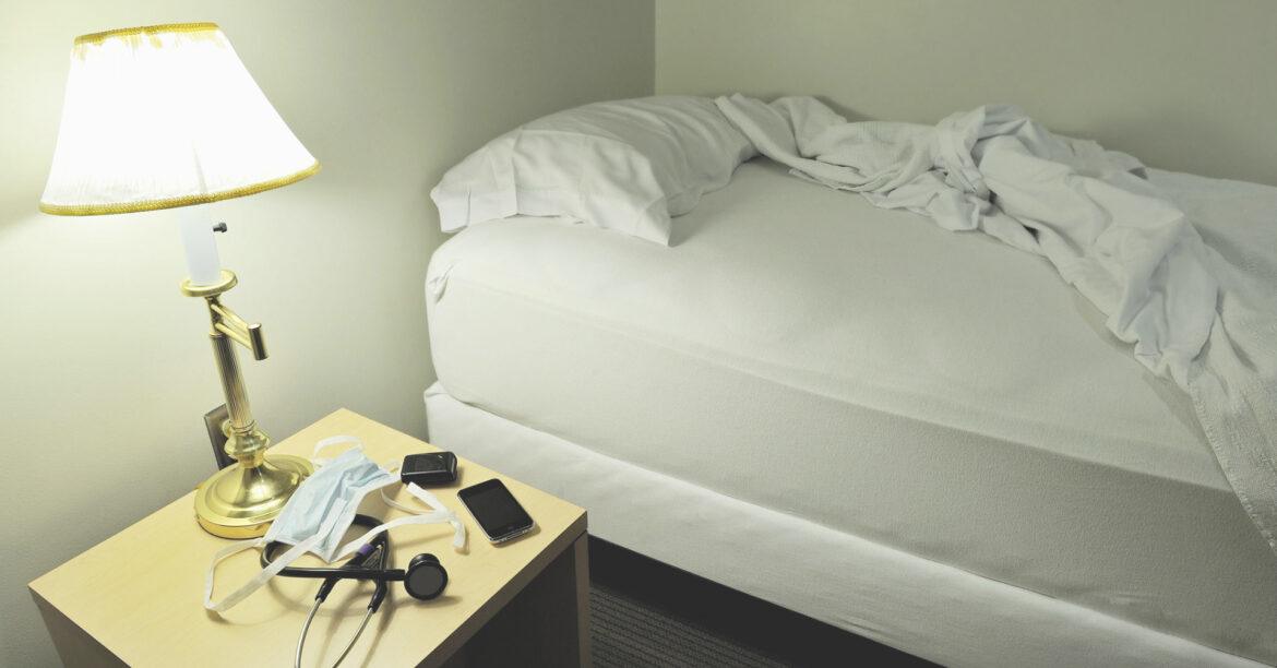A room in a sleep clinic shows a lamp, a twin bed with white sheets flipped open. On the nightstand is a phone, stethoscope and a mask. The American Psychological Association called sleep disorders an "epidemic." COVID-19 made things worse.