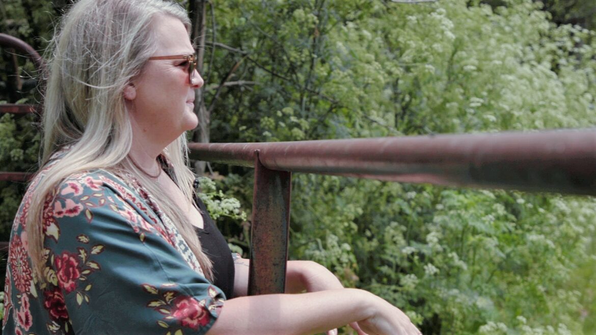 Jessica Piper is seen in profile with trees in the background.