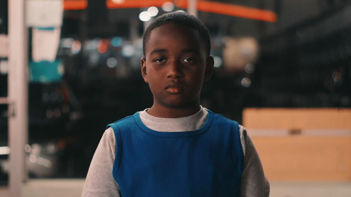 A boy in a laundromat stares at the camera in a scene for the movie "Vie."