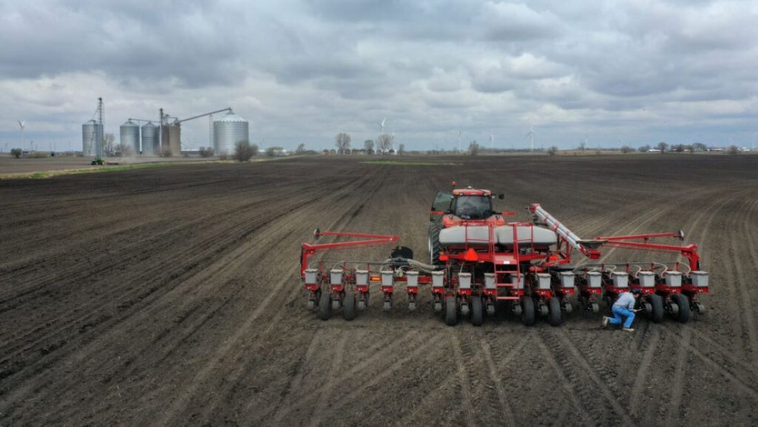 A farmer works on his planter in a field.
