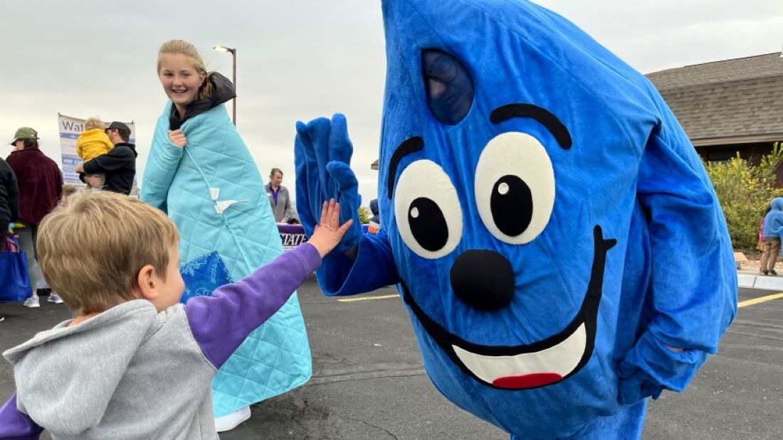 The Hays water conservation program's mascot, WaterSmart Wally, gives out high fives at a recent street fair. Wally is just one sign of how far the town's water-saving culture has come since the 1990s.
