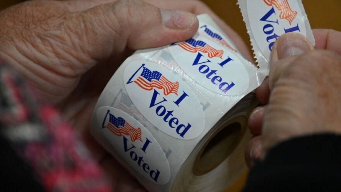 A poll worker peels off an "I Voted" sticker.
