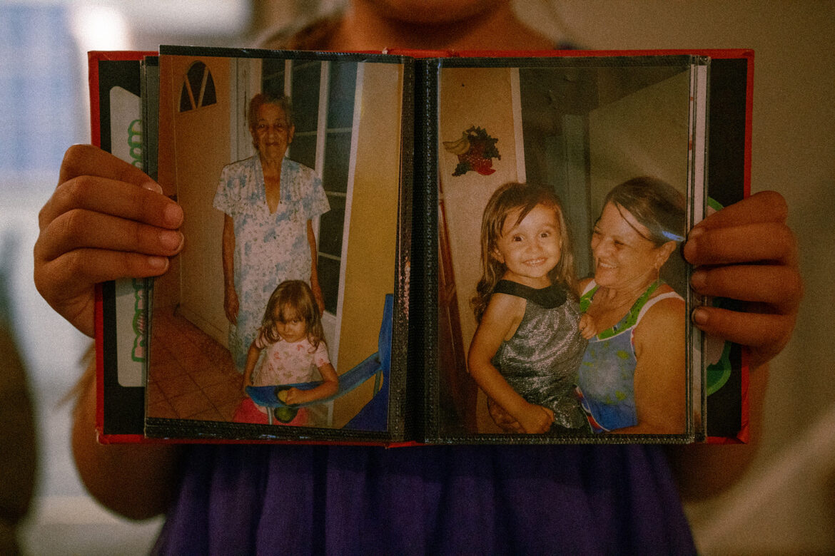 A photo album held by an eight year old's hands, displaying photos of her grandmother and great-grandmother. At the time, she and her parents were living in Puerto Rico. They moved to Kansas after hurricane Maria. ( Ji Stribling | Flatland)