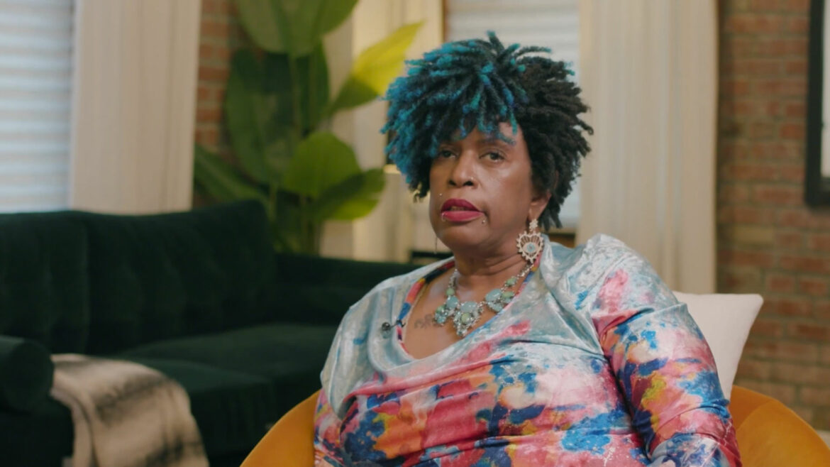 Woman with blue hair and colorful shirt sitting