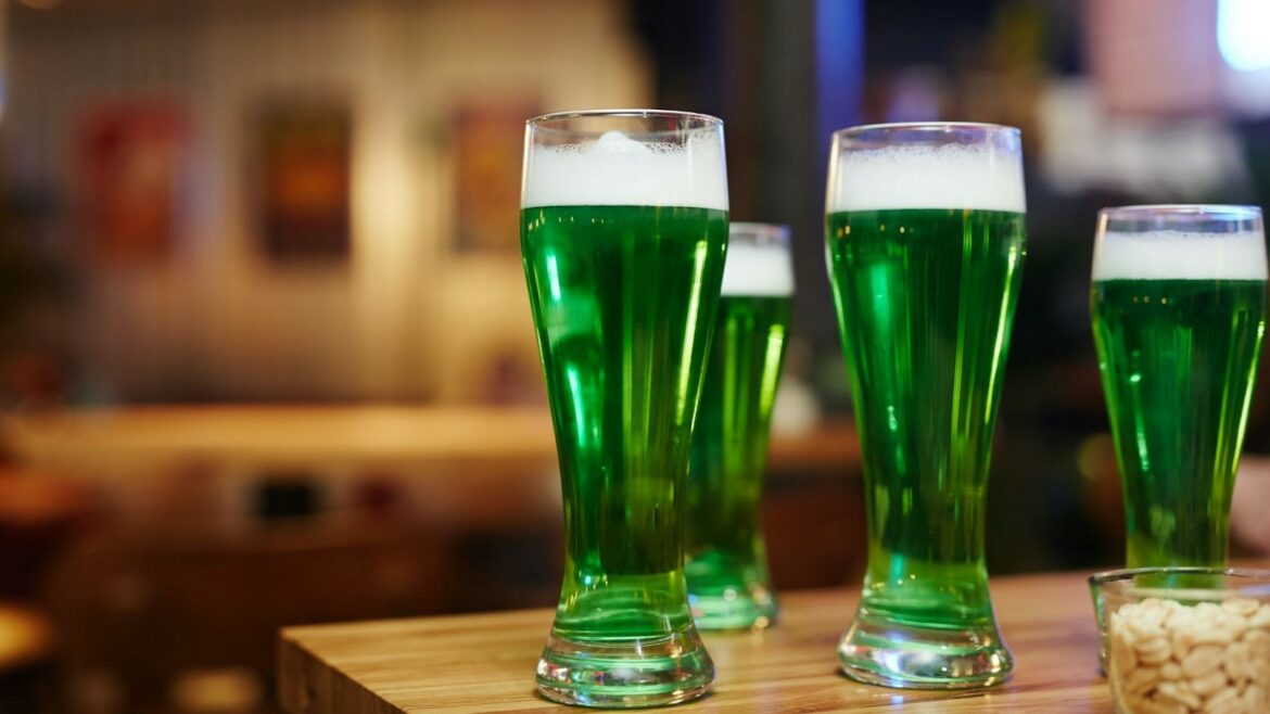 Four glasses of green beer on a bar.
