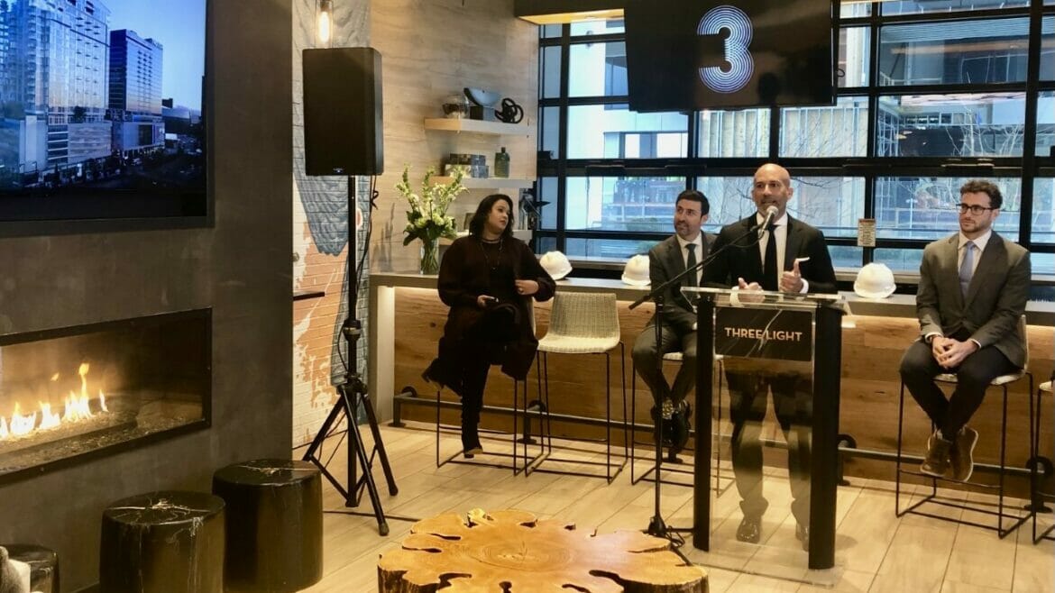 John Moncke, president of the Power & Light District, speaks at the Three Light topping-off event, City Manager Brian Platt is seated to his left, City Councilman Eric Bunch to his right.