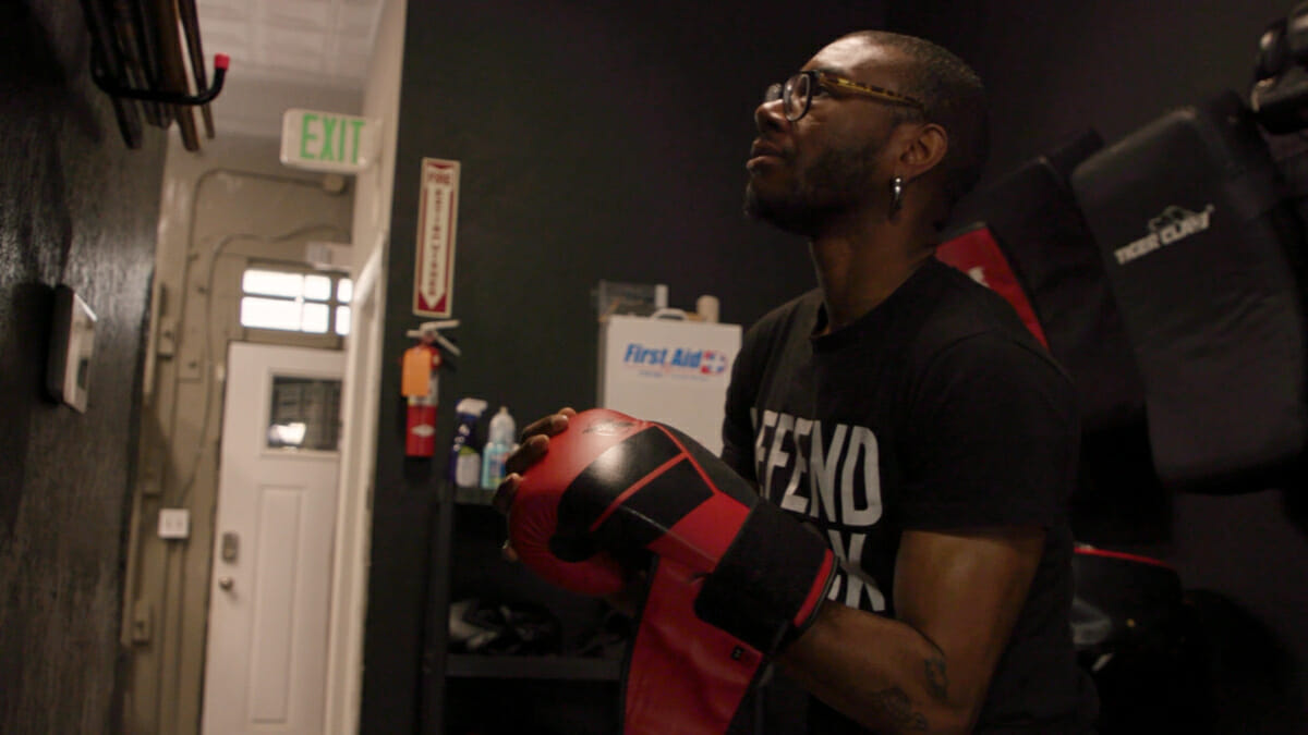 Person in glasses with boxing gloves in dark room